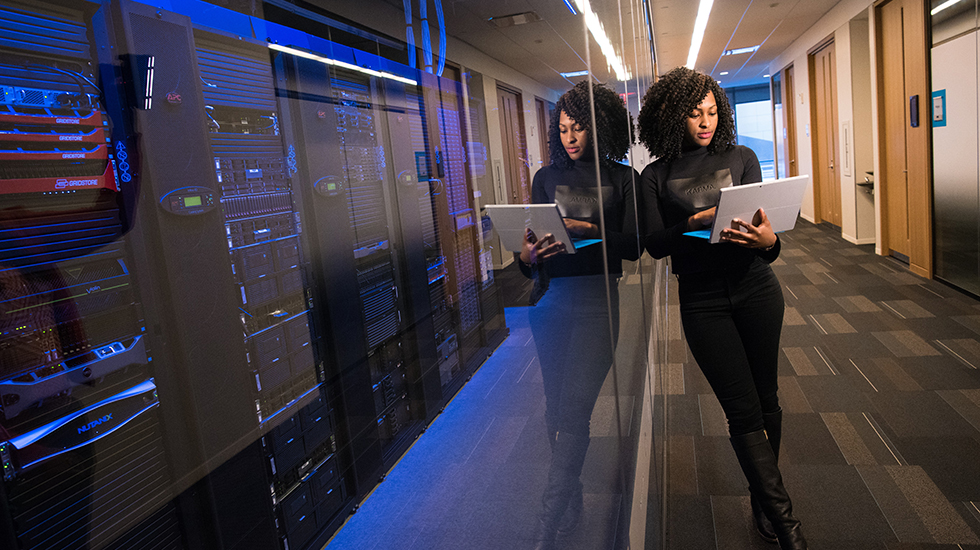 Apprentice standing next to server room with computer