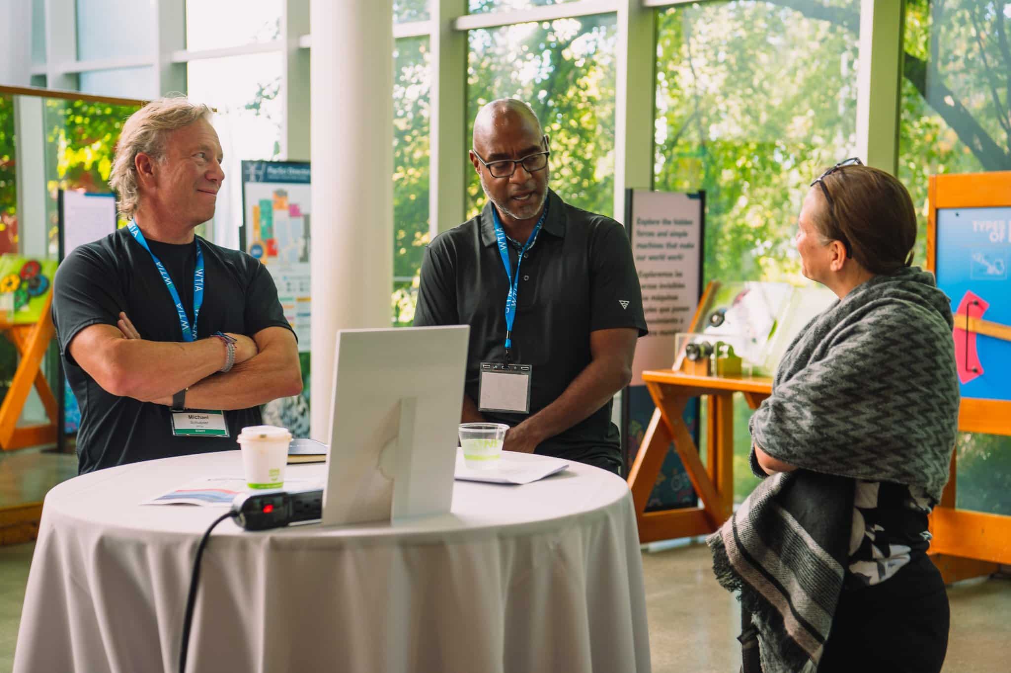 Three people are having a conversation at a table in a casual setting.