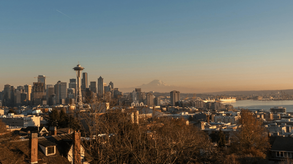 Seattle skyline with the Space Needle, harbor, and Mount Rainier in the distance.
